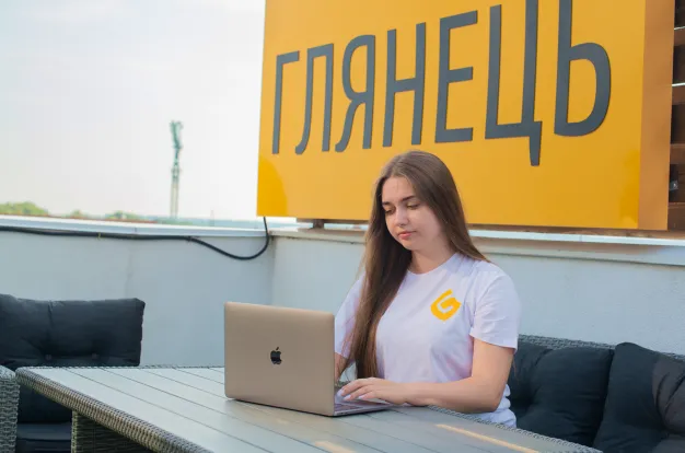 працівниця на тирасі із банером "Глянець" на фоні